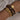 Gold chunky chain link bracelet and brown beaded bracelet on a wrist against a neutral background